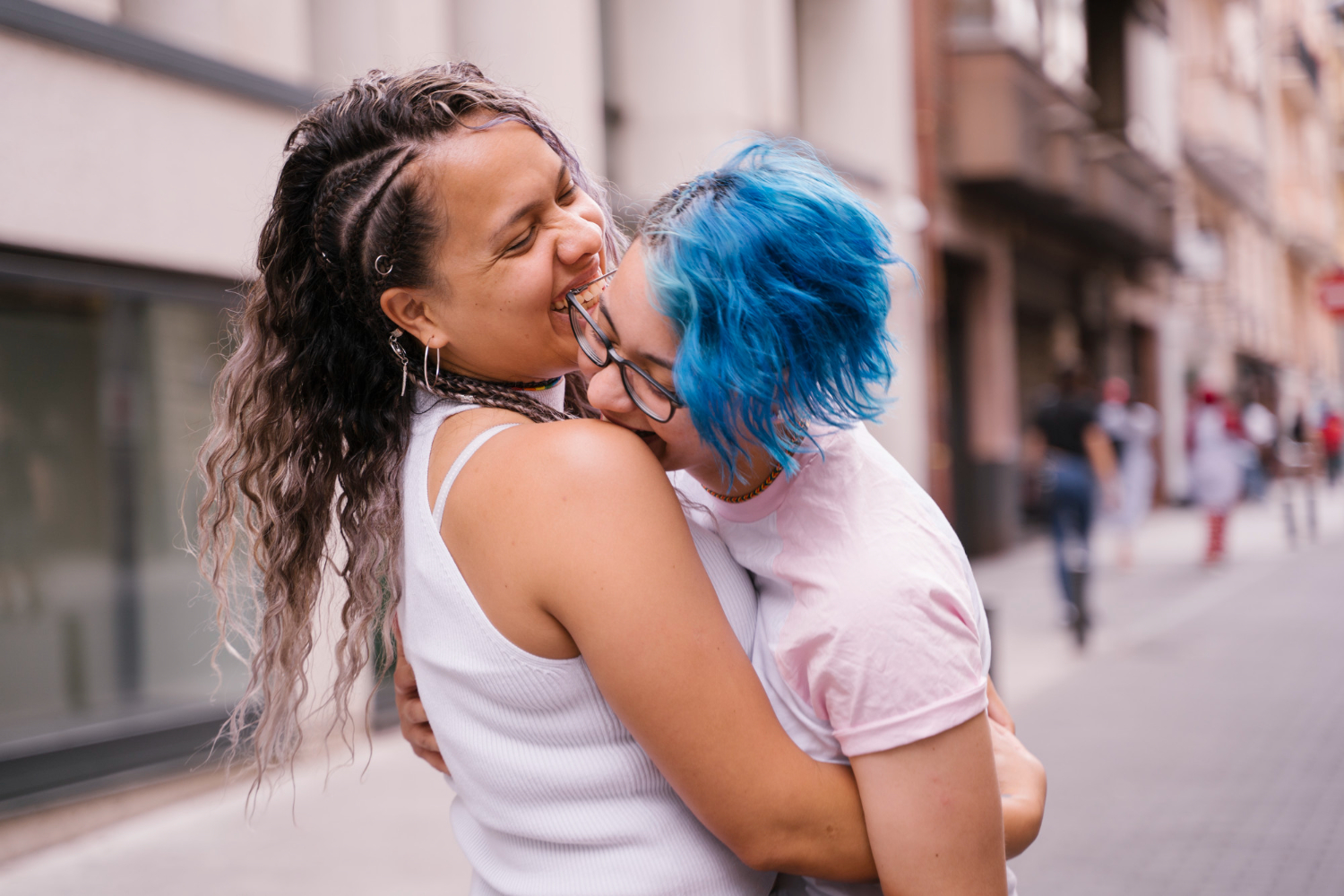 Two women sharing a joyful embrace on a city street